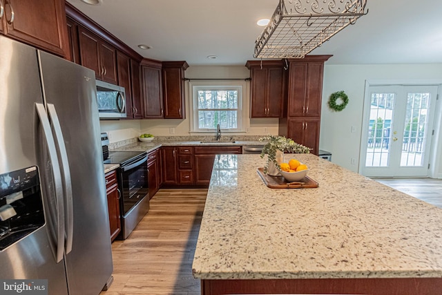 kitchen with a sink, stainless steel appliances, light wood-style floors, and a kitchen island