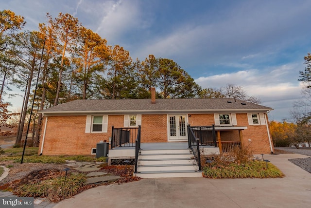 single story home featuring central air condition unit, french doors, brick siding, and a wooden deck