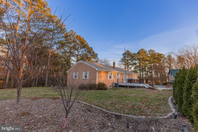 exterior space with a wooden deck, a yard, central AC unit, and a chimney