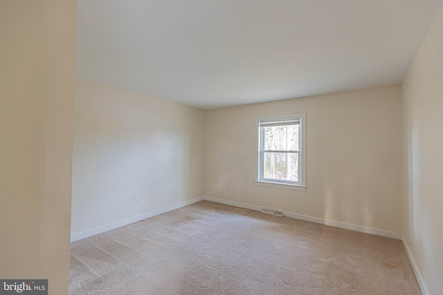 spare room featuring visible vents, baseboards, and light colored carpet