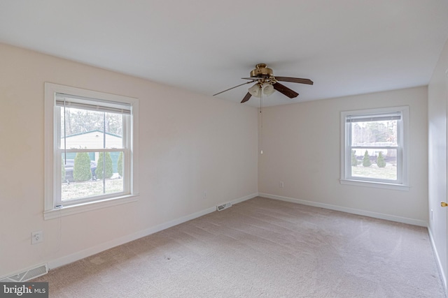 spare room featuring visible vents, light carpet, baseboards, and a ceiling fan