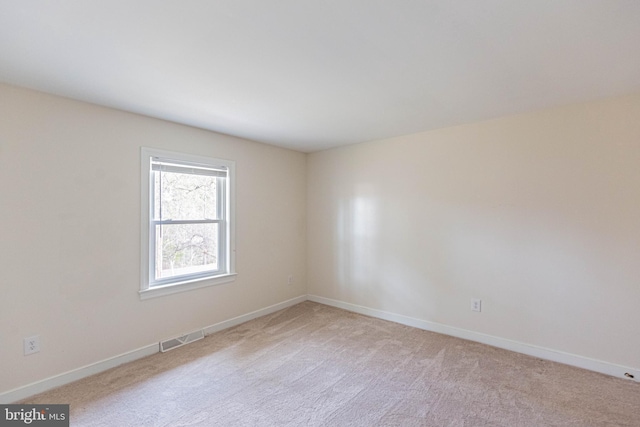 empty room with visible vents, baseboards, and light colored carpet