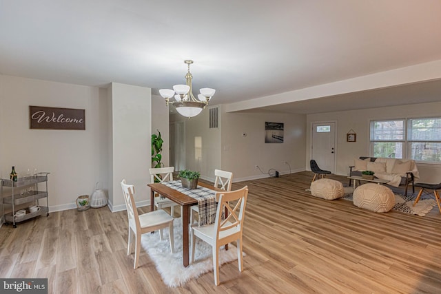 dining space featuring light wood-style flooring, a notable chandelier, baseboards, and visible vents