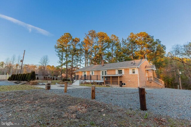 rear view of house featuring brick siding and a chimney