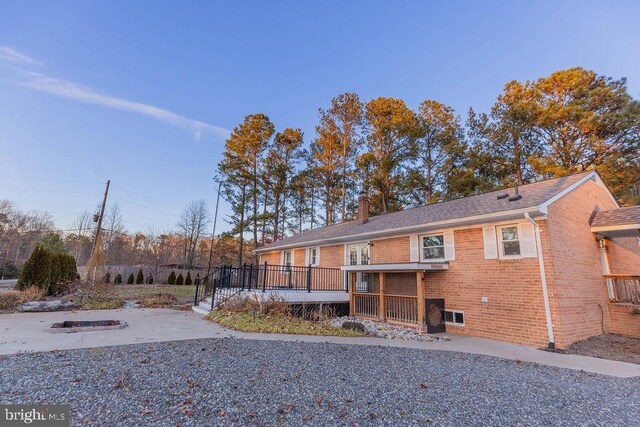 back of property featuring a chimney, brick siding, and a wooden deck