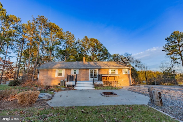 back of house with a patio, french doors, brick siding, and a chimney