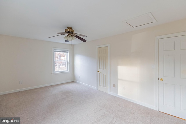 unfurnished room featuring a ceiling fan, attic access, light colored carpet, and baseboards