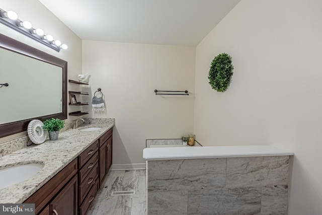 full bath featuring double vanity, baseboards, marble finish floor, and a sink