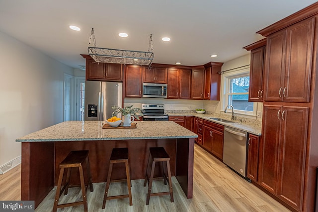 kitchen featuring visible vents, a center island, a breakfast bar, stainless steel appliances, and a sink