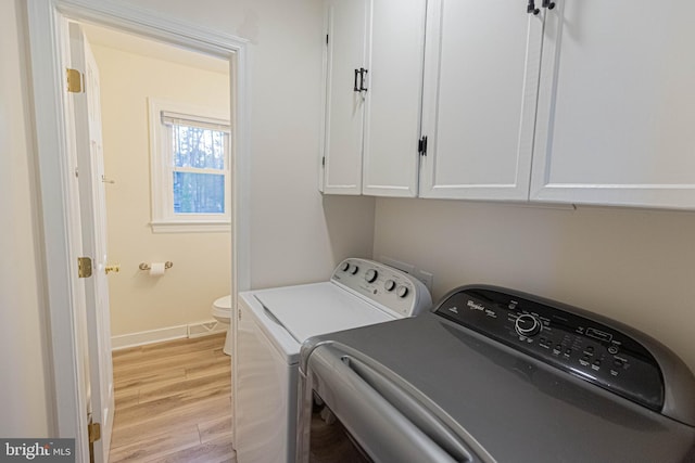 laundry area with cabinet space, baseboards, light wood-type flooring, and washing machine and clothes dryer