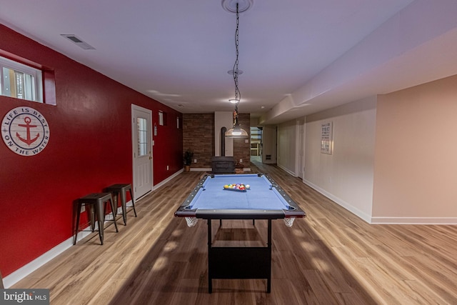 playroom with visible vents, baseboards, wood finished floors, and a wood stove