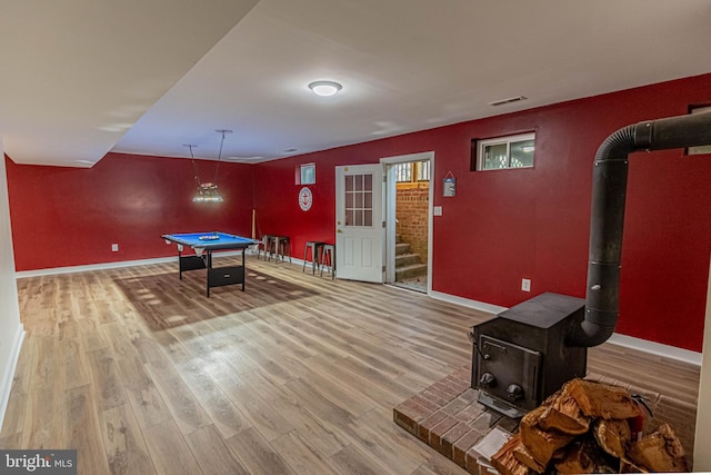 playroom with baseboards, pool table, wood finished floors, and a wood stove