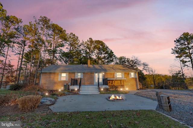 ranch-style house with a patio, a fire pit, brick siding, and a chimney