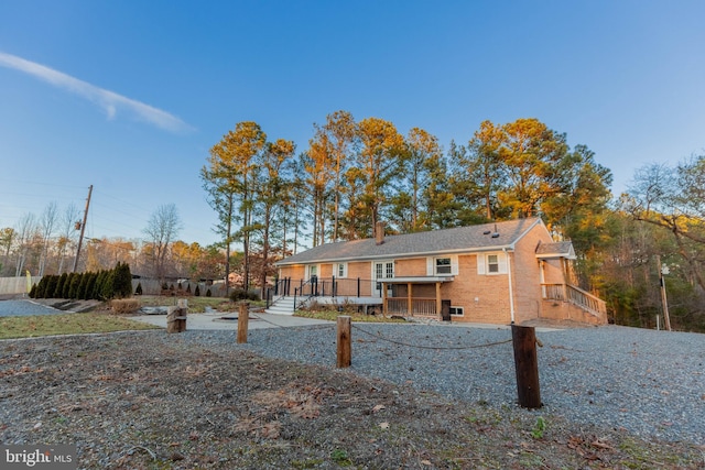 rear view of property featuring brick siding and a deck