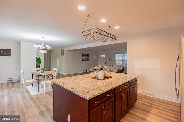 kitchen with visible vents, baseboards, freestanding refrigerator, light wood-style floors, and an inviting chandelier