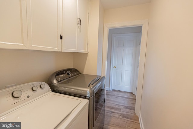 washroom featuring cabinet space, wood finished floors, separate washer and dryer, and baseboards