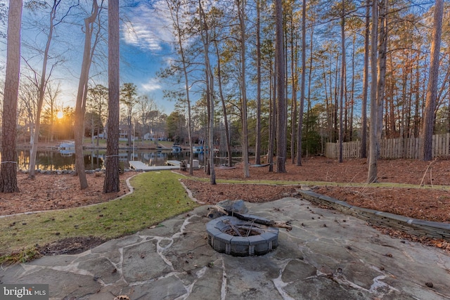 view of yard with fence, a water view, and a fire pit