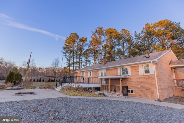 back of property featuring brick siding, a patio area, a chimney, and a wooden deck