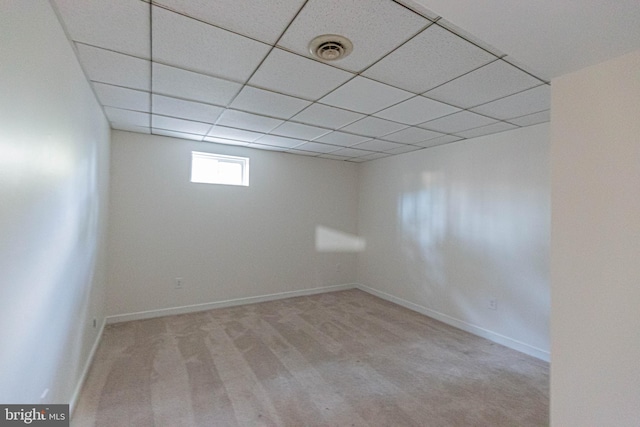 basement with a paneled ceiling, visible vents, carpet floors, and baseboards