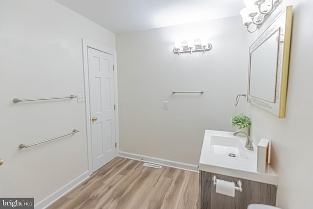 bathroom featuring vanity, an inviting chandelier, wood finished floors, and baseboards