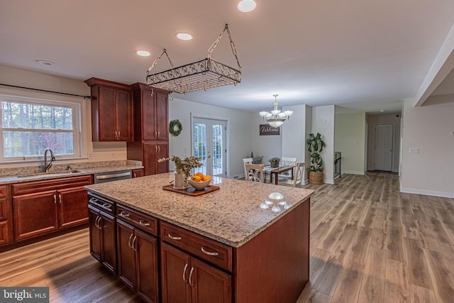 kitchen with light stone countertops, a kitchen island, light wood-type flooring, and a sink