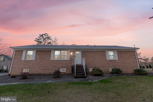 view of front facade with a lawn and brick siding