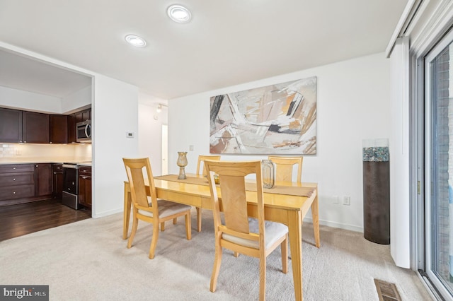 dining room featuring light carpet, visible vents, and baseboards