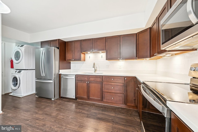 kitchen with a sink, stainless steel appliances, stacked washer / drying machine, and light countertops