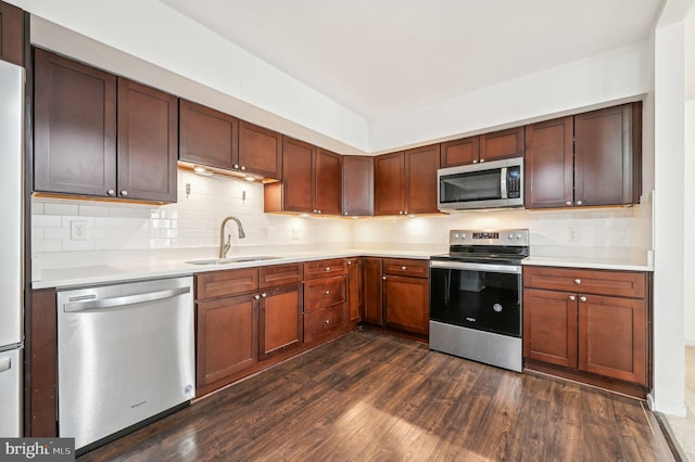 kitchen with appliances with stainless steel finishes, dark wood-style flooring, light countertops, and a sink