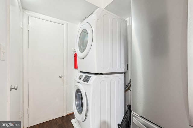 washroom featuring dark wood-style flooring, laundry area, and stacked washing maching and dryer