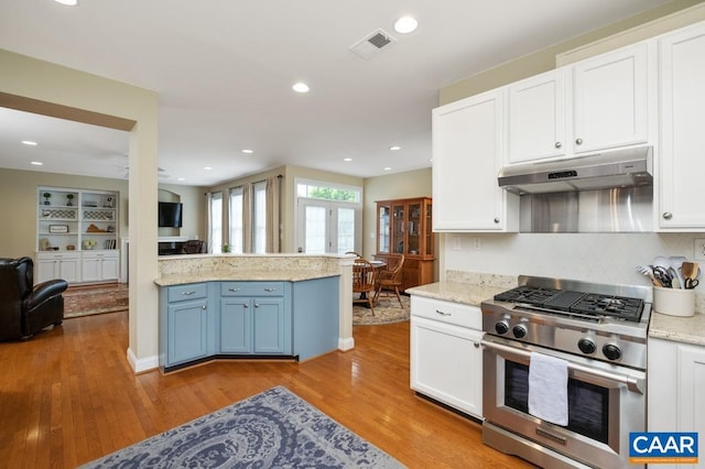 kitchen featuring white cabinets, under cabinet range hood, light countertops, and gas stove