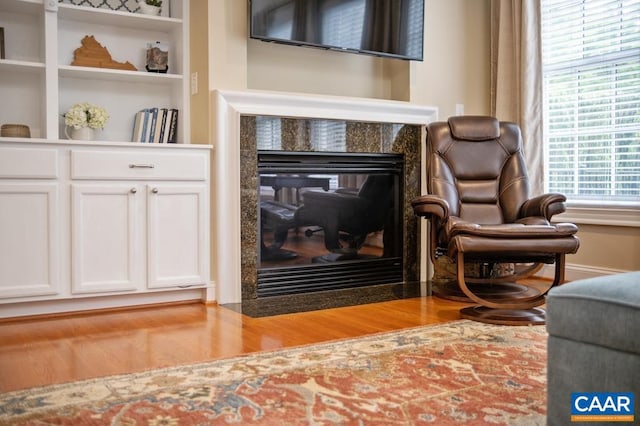 sitting room with a tiled fireplace, wood finished floors, and baseboards