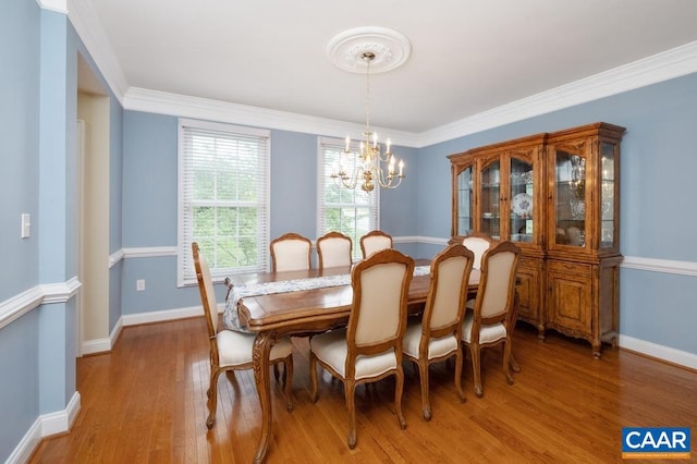 dining space with a chandelier, crown molding, baseboards, and wood finished floors