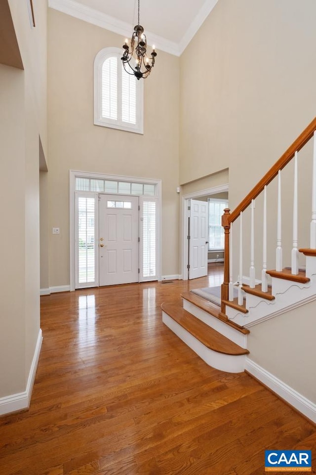 foyer featuring baseboards, stairway, wood finished floors, and crown molding