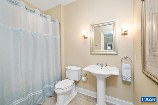 bathroom featuring a shower with shower curtain, toilet, a sink, tile patterned flooring, and baseboards