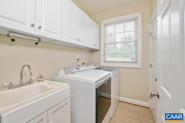 laundry area featuring cabinet space, baseboards, washing machine and dryer, a sink, and light tile patterned flooring