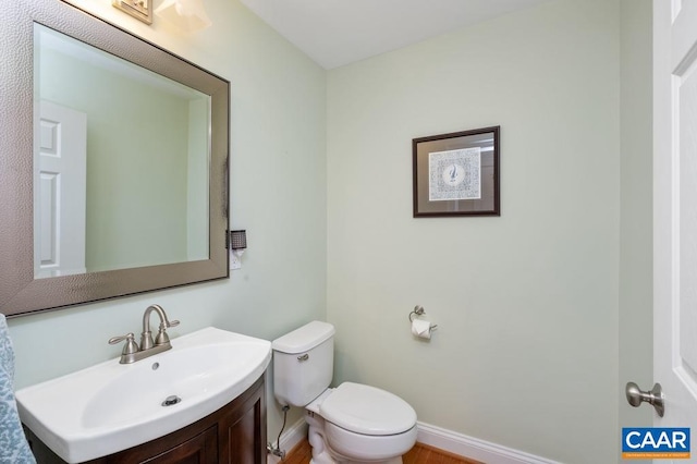 bathroom with baseboards, vanity, and toilet