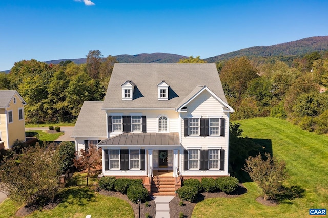 view of front of property featuring metal roof, a standing seam roof, stairs, a mountain view, and a front lawn