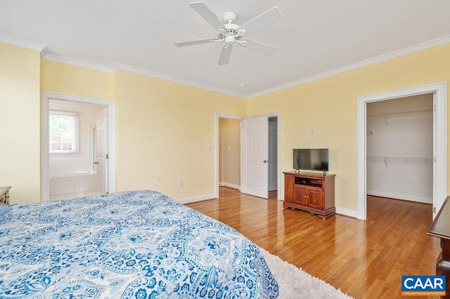 bedroom featuring ornamental molding, a walk in closet, baseboards, and wood finished floors