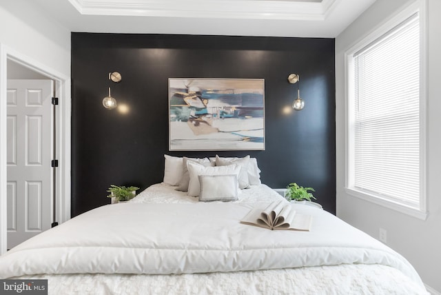 bedroom with an accent wall and ornamental molding