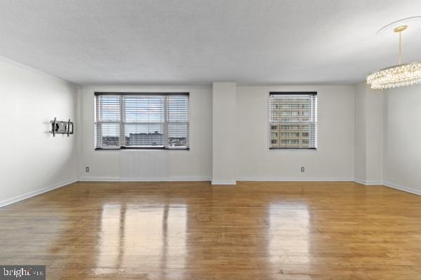 empty room with a healthy amount of sunlight, baseboards, and wood finished floors