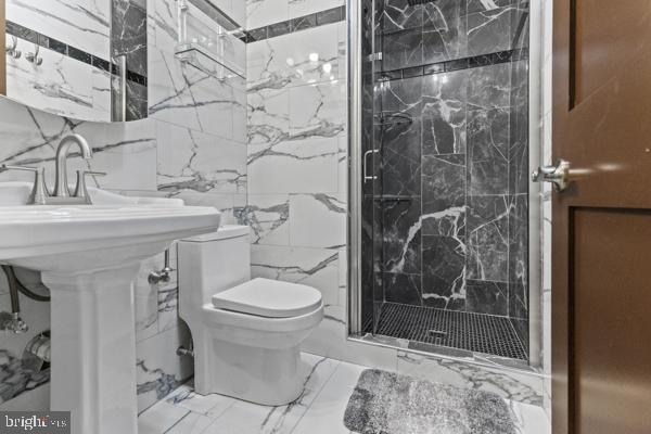 full bath featuring toilet, marble finish floor, and a marble finish shower