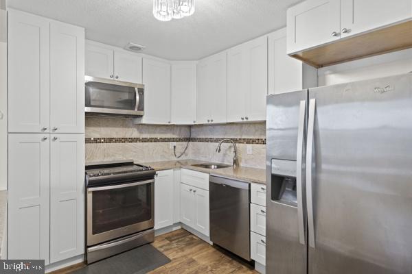 kitchen featuring appliances with stainless steel finishes, light countertops, dark wood-style flooring, and white cabinetry