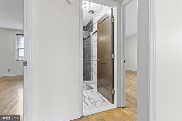 hallway featuring light wood-style flooring and baseboards