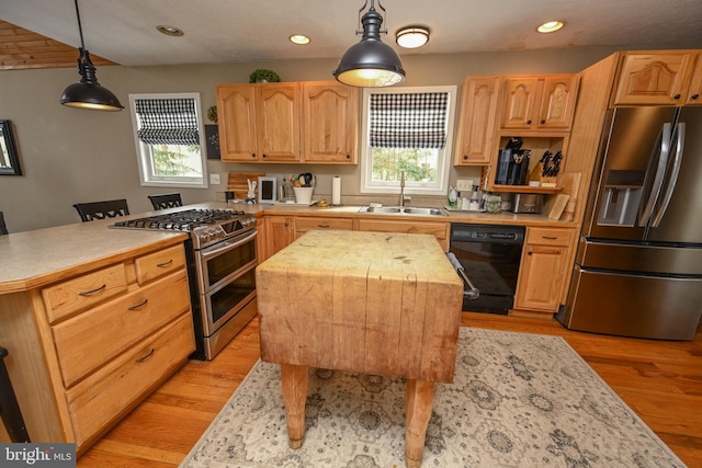 kitchen with a kitchen island, stainless steel appliances, a sink, and decorative light fixtures