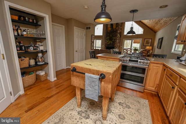 kitchen featuring light countertops, hanging light fixtures, light wood-style floors, and double oven range