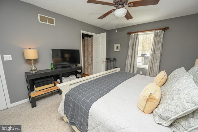 carpeted bedroom featuring a ceiling fan, visible vents, and baseboards