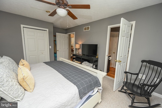 bedroom with light carpet, baseboards, visible vents, a textured ceiling, and a closet