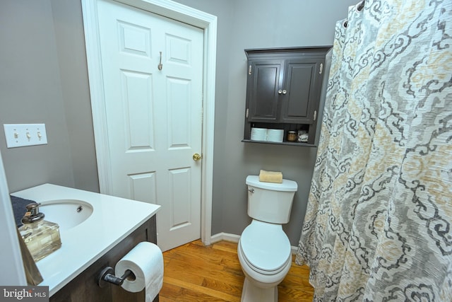 full bathroom with toilet, vanity, baseboards, and wood finished floors