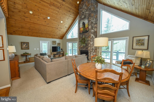 dining room with light carpet, wood ceiling, a fireplace, and a wealth of natural light